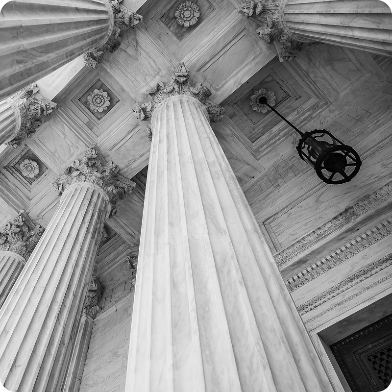 Black and white view looking up at court house columns and ceiling